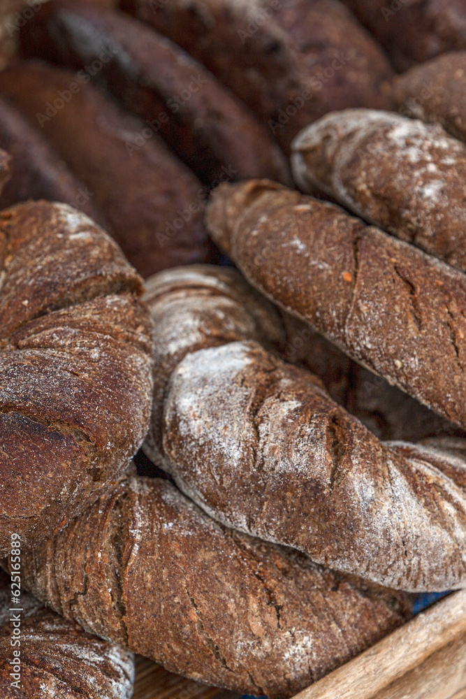 Lots of round dark bread on the counter. Traditional pastries. Close-up. Selective focus. Vertical.