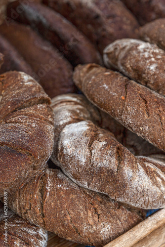 Lots of round dark bread on the counter. Traditional pastries. Close-up. Selective focus. Vertical.