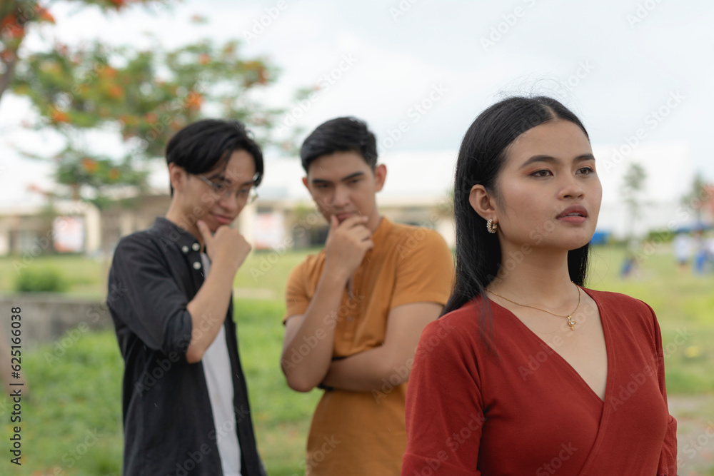 An unsettled young asian woman tries to ignore two men checking out her body or catcalling. An unsettled young asian woman tries to ignore two men checking out her body or catcalling.