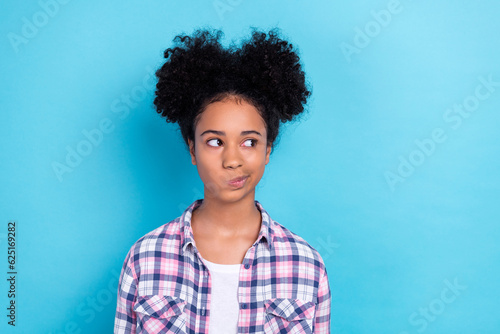 Portrait of minded friendly person with afro hairstyle wear plaid shirt thoughtfully look empty space isolated on blue color background © deagreez