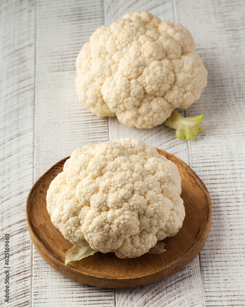 Raw white cauliflower on a white wooden background. Seasonal vegetables. Raw white cauliflower on a white wooden background. Seasonal vegetables.