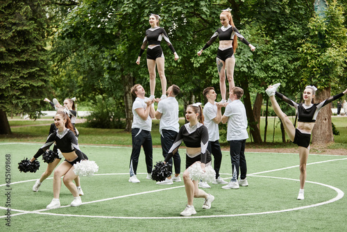 фотографія Cheerleader team doing tricks and dancing with pompom at sport competition outdo