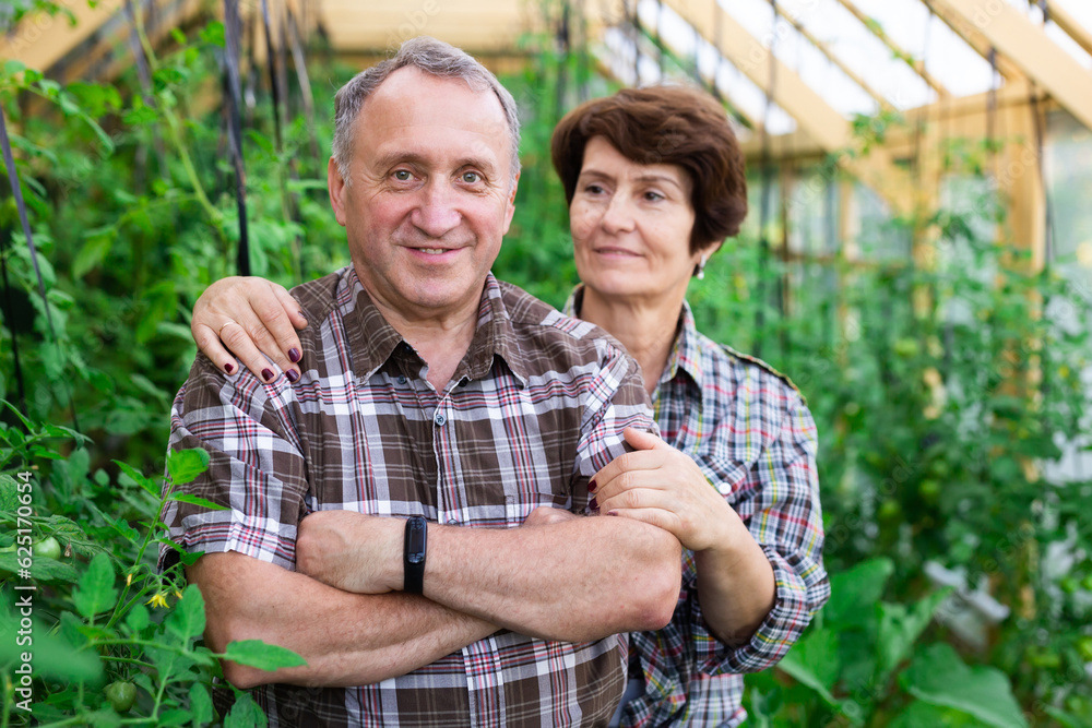 Portrait of happy elderly couple in the greenhouse Portrait of happy elderly couple in the greenhouse