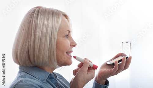 Feminine Grace mesmerizing. A woman s delicate hands and face in profile expertly adorning her face with makeup  as she prepares for a special occasion. Woman is doing makeup in front of the mirror.