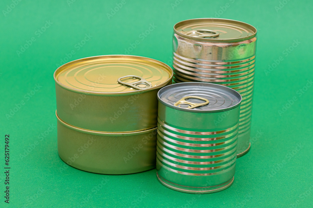 A Group of Stacked Tin Cans with Blank Edges on Green Background. Canned Food. Different Aluminum Cans for Safe and Long Term Storage of Food. Steel Sealed Food Storage Containers A Group of Stacked Tin Cans with Blank Edges on Green Background. Canned Food. Different Aluminum Cans for Safe and Long Term Storage of Food. Steel Sealed Food Storage Containers
