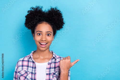 Photo of impressed astonished teenager dressed checkered shirt indicating at big sale empty space isolated on blue color background