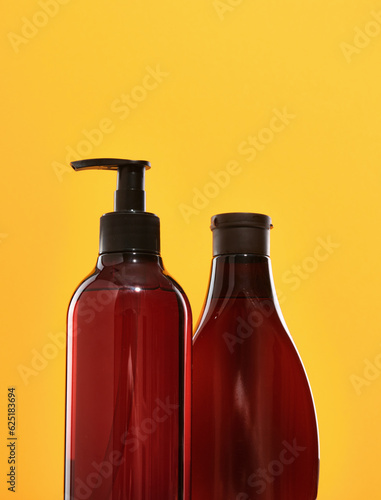 Dispenser and bottle of dark brown color with shower gel and liquid soap.
