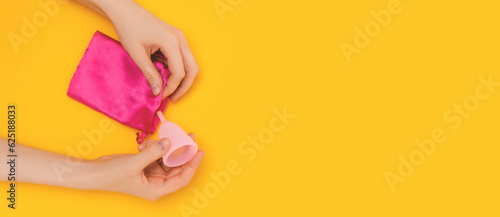 Wallpaper Mural Banner with female hands take out the menstrual cup from the pink bag. Zero waste period concept on a yellow background. Place for text. Torontodigital.ca
