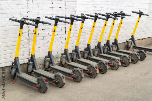 A lot of electric scooters against a white brick wall