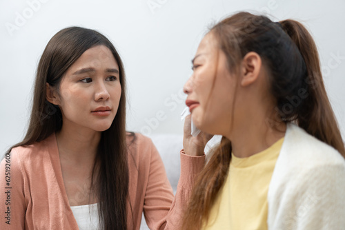 Two women talking about problems at home. Asian women embrace to calm their sad best friends from feeling down. Female friends supporting each other. Problems, friendship, and care concept