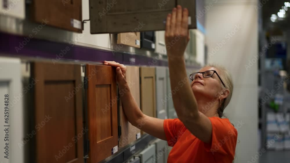 Pretty mature woman looking at cabinet doors for kitchen and bathroom in a hardware store. Pretty mature woman looking at cabinet doors for kitchen and bathroom in a hardware store.