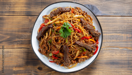 Top view on uyghur cuisine dish tsomyan fried noodles with beef on the wooden table, horizontal