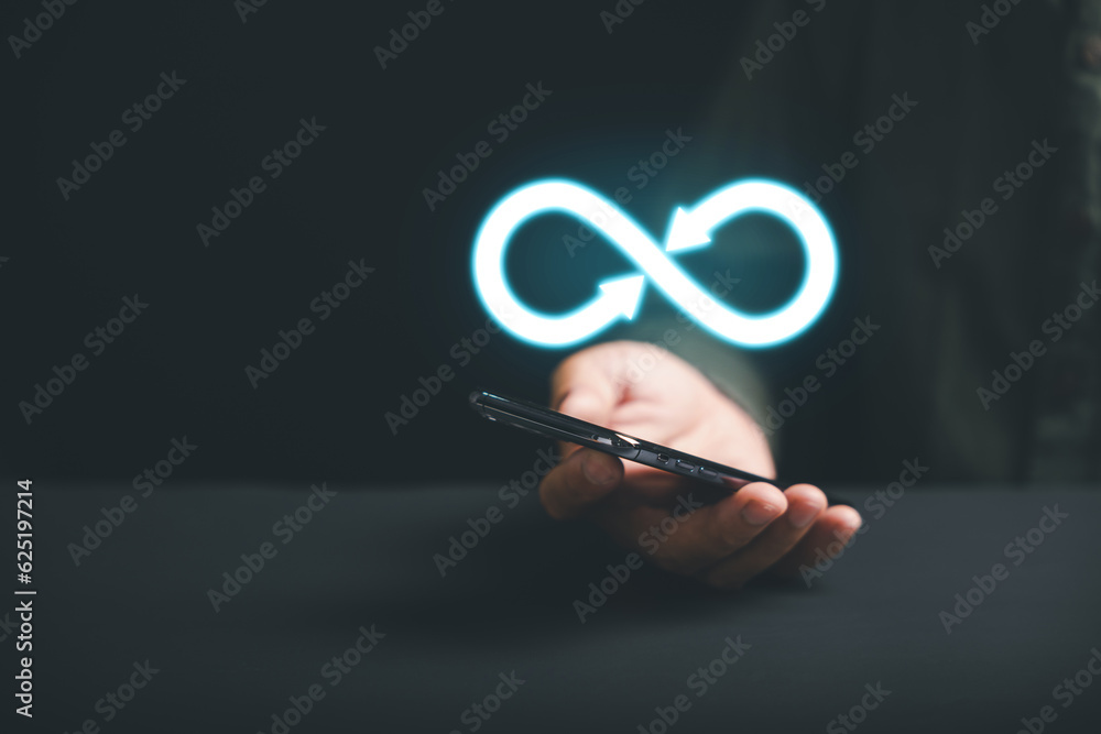 Businessman holds smartphone with infinity symbol, representing