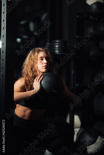Athletic Beautiful Woman squatting with ball at gym.  © teksomolika