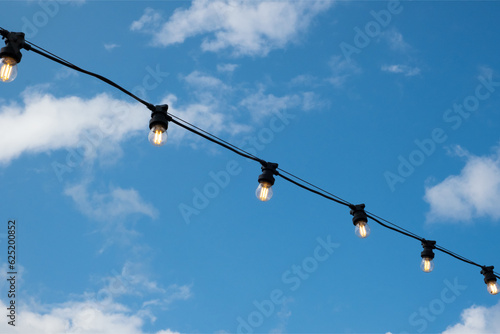 White energy-saving light bulbs on a wire, blue sky, a beautiful decoration for the evening city.