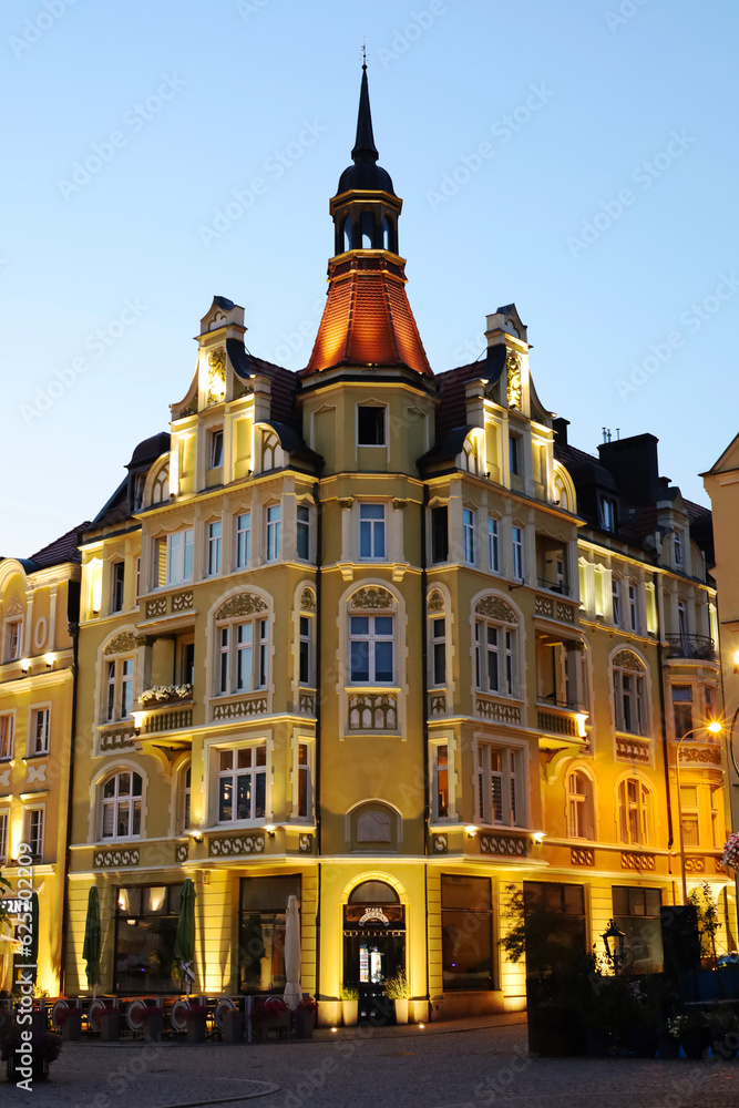 Obraz premium Yellow architectural building on the square in Bolesławiec. Bolesławiec city center.City square, hall. Sunset in the center of Bolesławiec. Polish.European city.Rays of light illuminate the building.