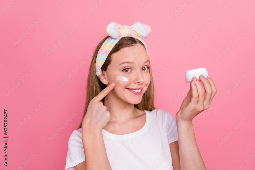 Portrait of adorable positive person hand hold peeling cream jar finger point apply cream under eye isolated on pink color background Portrait of adorable positive person hand hold peeling cream jar finger point apply cream under eye isolated on pink color background