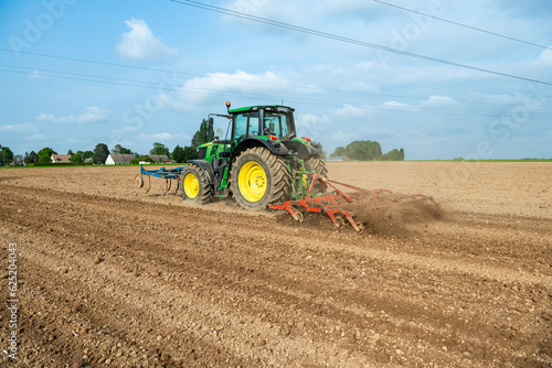 Travail du sol avant semis. Passage d'un rouleau vibroculteur brise-mottes. Agricultrice au volant du tracteur