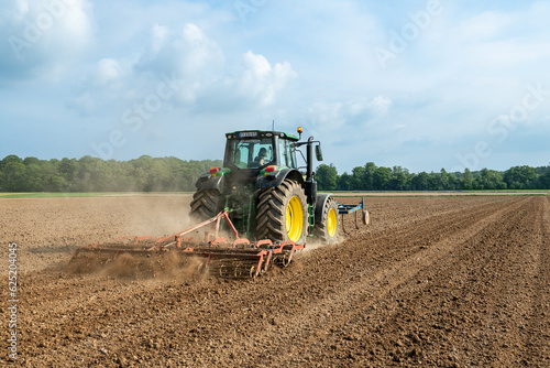 Travail du sol avant semis. Passage d'un rouleau vibroculteur brise-mottes. Agricultrice au volant du tracteur