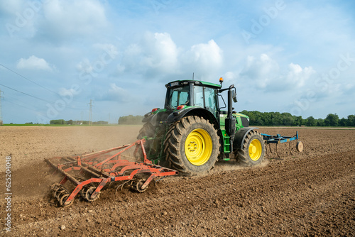 Travail du sol avant semis. Passage d'un rouleau vibroculteur brise-mottes. Agricultrice au volant du tracteur