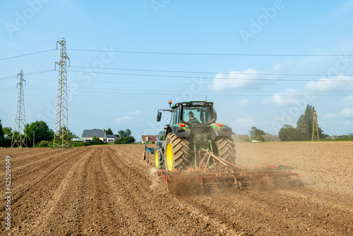 Travail du sol avant semis. Passage d'un rouleau vibroculteur brise-mottes. Agricultrice au volant du tracteur