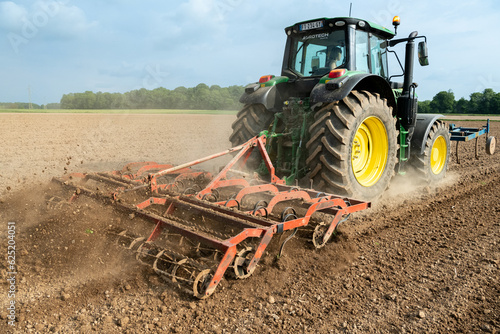 Travail du sol avant semis. Passage d'un rouleau vibroculteur brise-mottes. Agricultrice au volant du tracteur