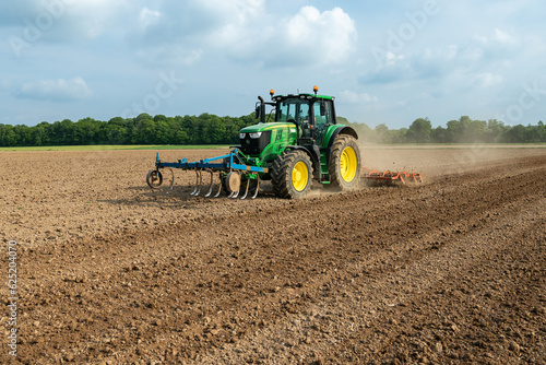 Travail du sol avant semis. Passage d'un rouleau vibroculteur brise-mottes. Agricultrice au volant du tracteur