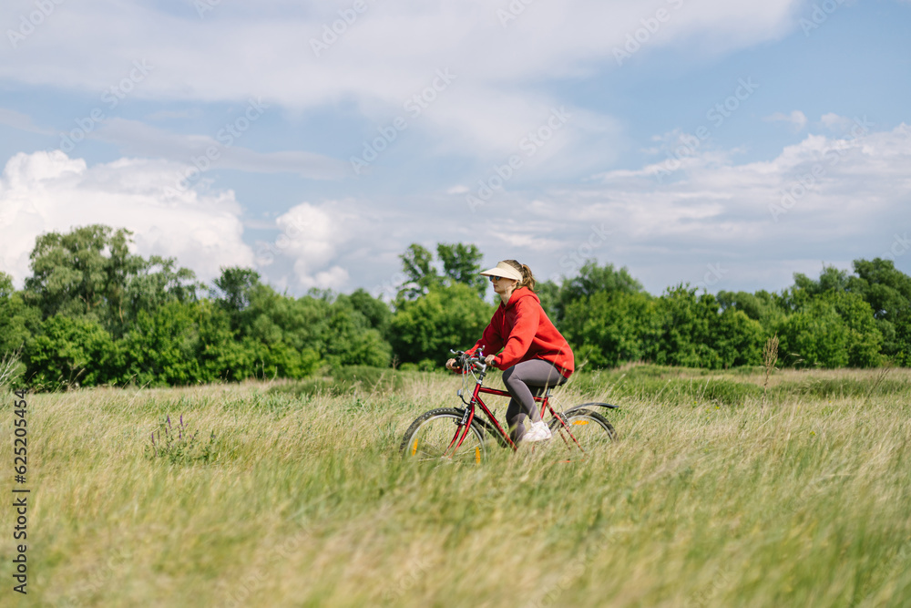 Obraz premium young girl riding a bike in nature in summer