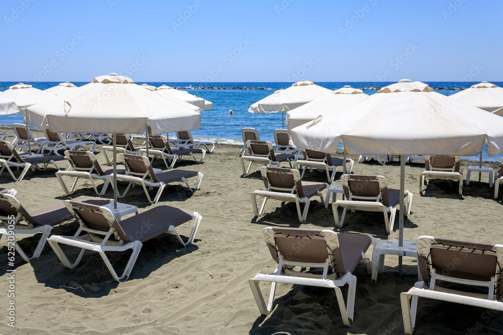 Empty sun beds and umbrellas on sandy sea beach, Limassol, Cyprus