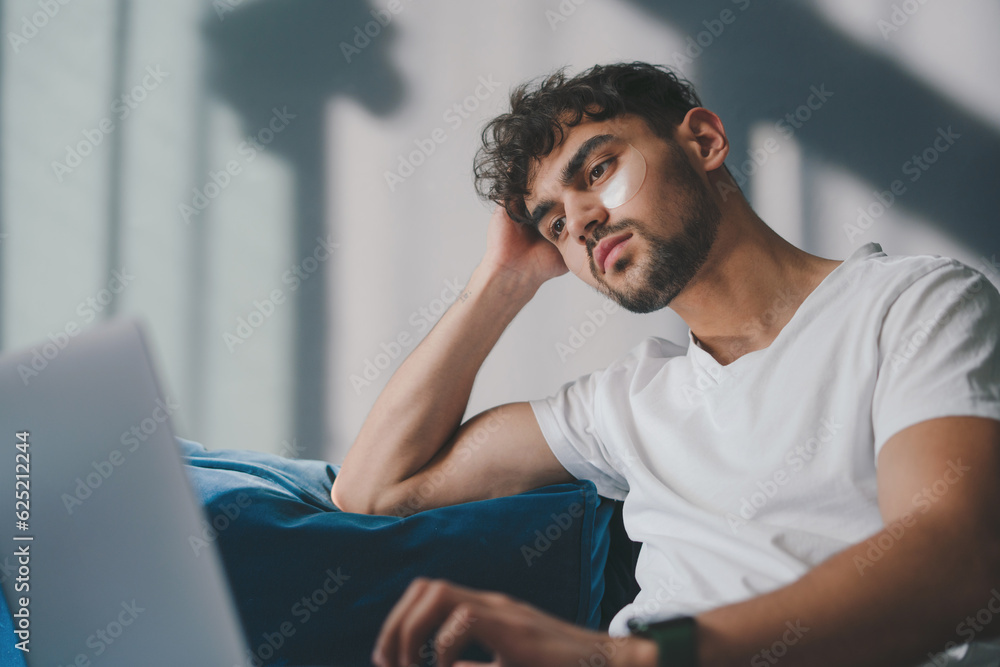 Handsome homey guy sitting comfy on sofa, browsing notebook freelancer remote stay home on the weekend. Social distancing. Self Isolation. Handsome homey guy sitting comfy on sofa, browsing notebook freelancer remote stay home on the weekend. Social distancing. Self Isolation.
