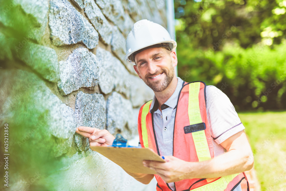 Fototapeta premium Man with a white hard hat holding a clipboard, inspect house
