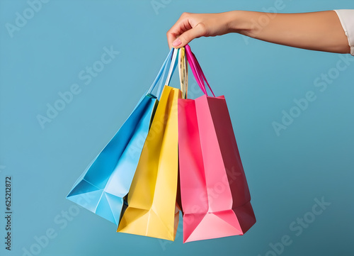 Female hand holding many colorful shopping bags on blue background, template - ai generative