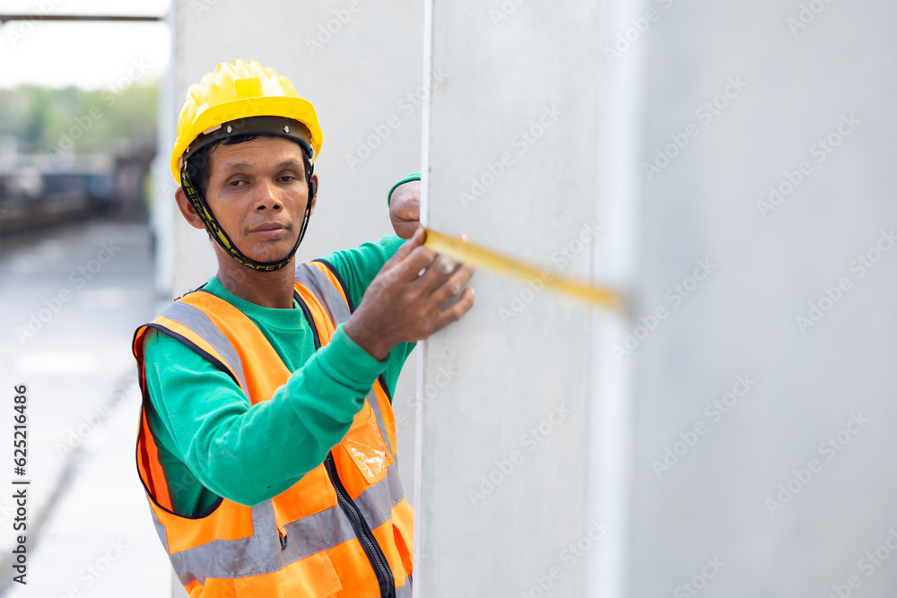 Senior asian man worker using measure tape and working at precast concrete wall factory. Yellow tape measure construction tools. Heavy Industry Manufacturing Factory Senior asian man worker using measure tape and working at precast concrete wall factory. Yellow tape measure construction tools. Heavy Industry Manufacturing Factory