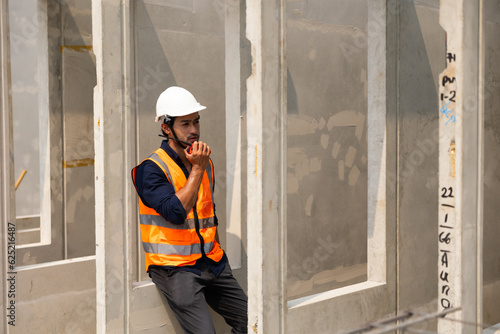 radio transmitter. Asian indian architect Engineering man in safety hardhat talking on walkie talkie at factory facilities. Heavy Industry Manufacturing Factory. Prefabricated concrete walls