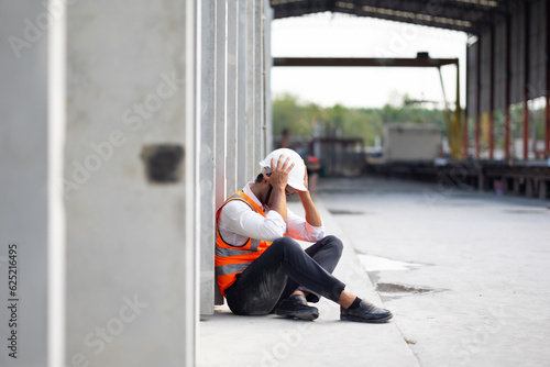 Unhappy lonely depressed and sad feeling. Asian Engineer man working at precast factory. Engineering worker in safety hardhat at factory industrial facilities