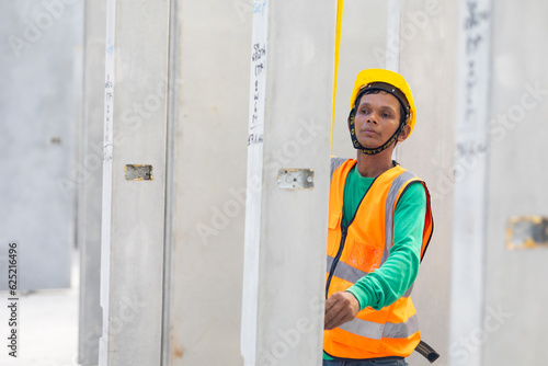 Senior asian man worker using measure tape and working at precast concrete wall factory. Yellow tape measure construction tools. Heavy Industry Manufacturing Factory
