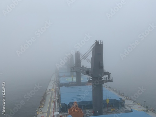View from the bridge of the handymax bulk carrier to the holds in the fog. Large cargo ship in the river photo