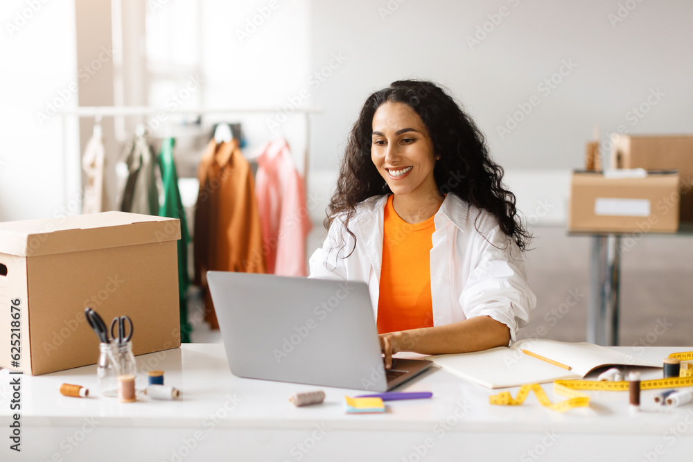 Fashion Designer Arabic Lady Websurfing On Laptop Working In Showroom Fashion Designer Arabic Lady Websurfing On Laptop Working In Showroom