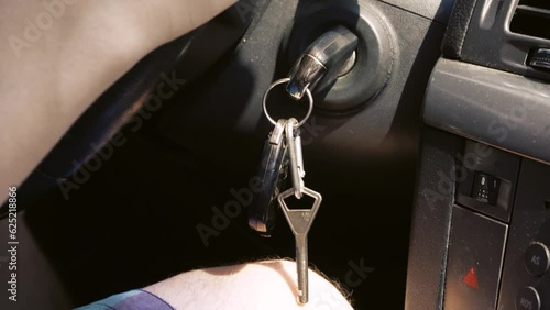 Keys in the ignition. Close-up of a key in a car ignition. Man's hand hold the steering wheel while driving the car. photo