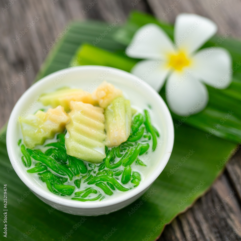 Appetizing lod chong placed on a green banana leaf decorated with white champa flowers on a wooden table. Appetizing lod chong placed on a green banana leaf decorated with white champa flowers on a wooden table.