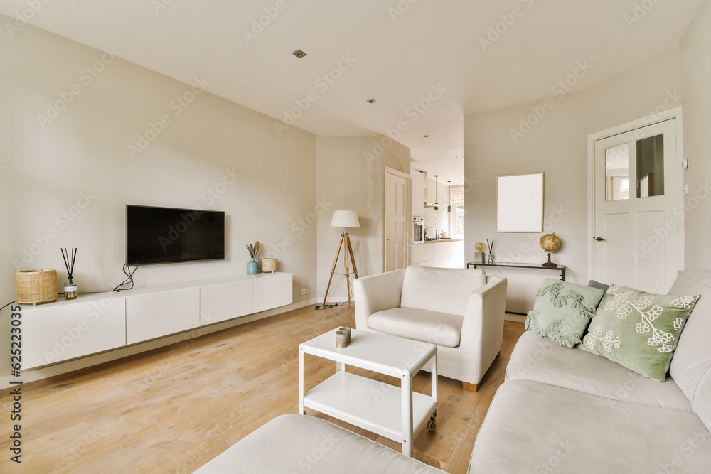 a living room with wood flooring and white couches in front of a flat screen tv on the wall a living room with wood flooring and white couches in front of a flat screen tv on the wall