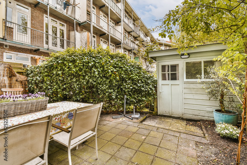 a patio with chairs and table in the middle of an apartment complex, surrounded by trees and plants on a sunny day © Casa imágenes