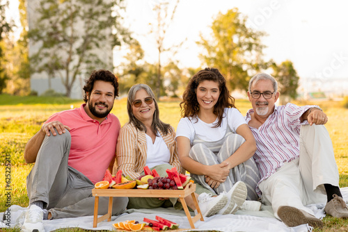 Glad european old and adult family enjoy picnic, talk, fruits and eat food #625225213
