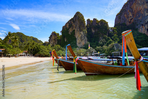 Traditional Thai longtail boats beached on the golden sand of Railay West Beach in front of rocky karst outcrops in the Province of Krabi, Thailand, Southeast Asia
