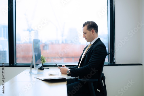 Business man using smartphone on his working desk with high building, new generation office. Business new eged or era. photo