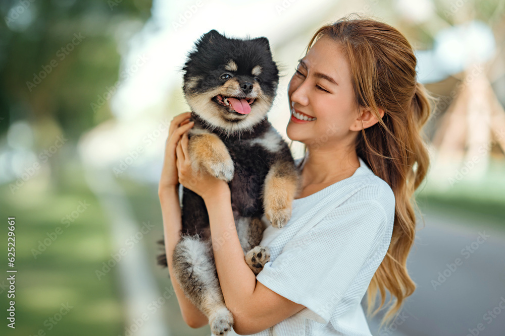 Obraz premium Happy asian woman playing with dog together in park outdoors, summer vacation.