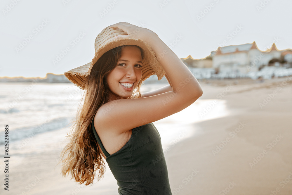 Summer holidays and leisure concept. Happy european woman in swimsuit and straw hat walking along beach, free space