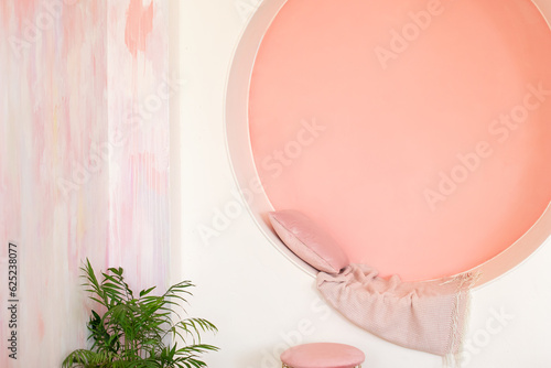 Modern style conceptual interior room. Modern Living room design vibrant interior with decorative arch on pink wall with pillows and plaid. Memphis style interior with niche arch for seat. Arch window
