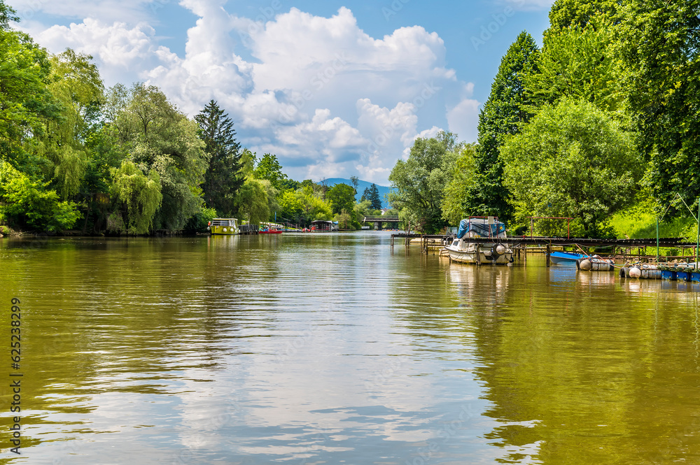 A view past moored boats on the Ljubljanica River on the outskirts of Ljubljana, Slovenia in summertime