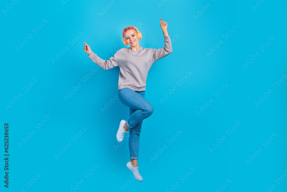 Full body portrait of energetic excited lady jumping dancing enjoy song empty space isolated on blue color background Full body portrait of energetic excited lady jumping dancing enjoy song empty space isolated on blue color background